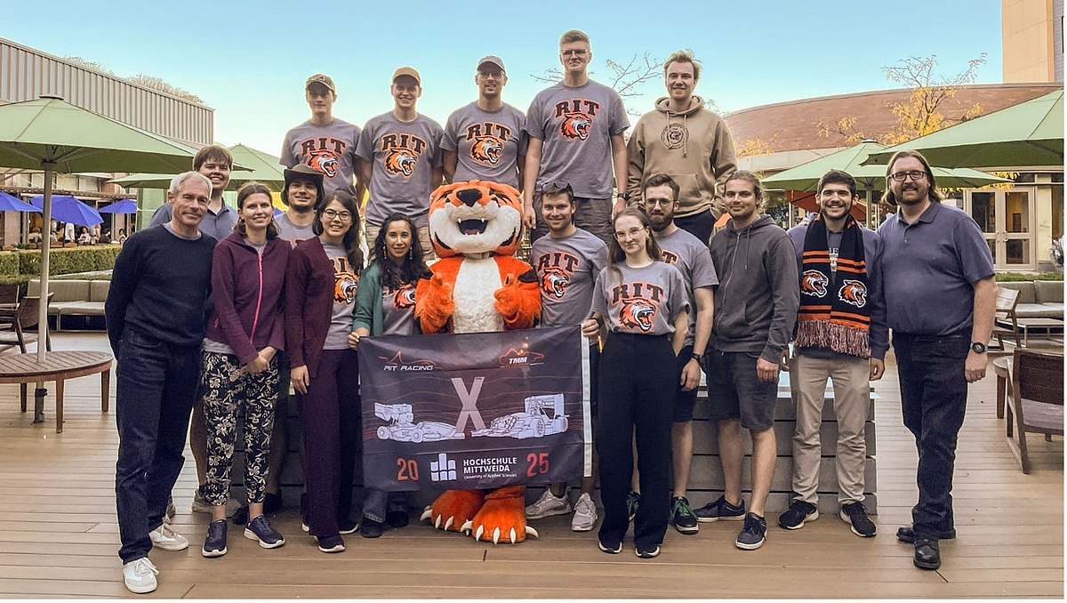 Abschied mit Ritchie the Tiger, dem Maskottchen des RIT. Gruppenfoto mit lebensgroßem Tiger-Maskottchen und den Teilnehmenden, eine von ihnen tragen RIT-Shirts.
