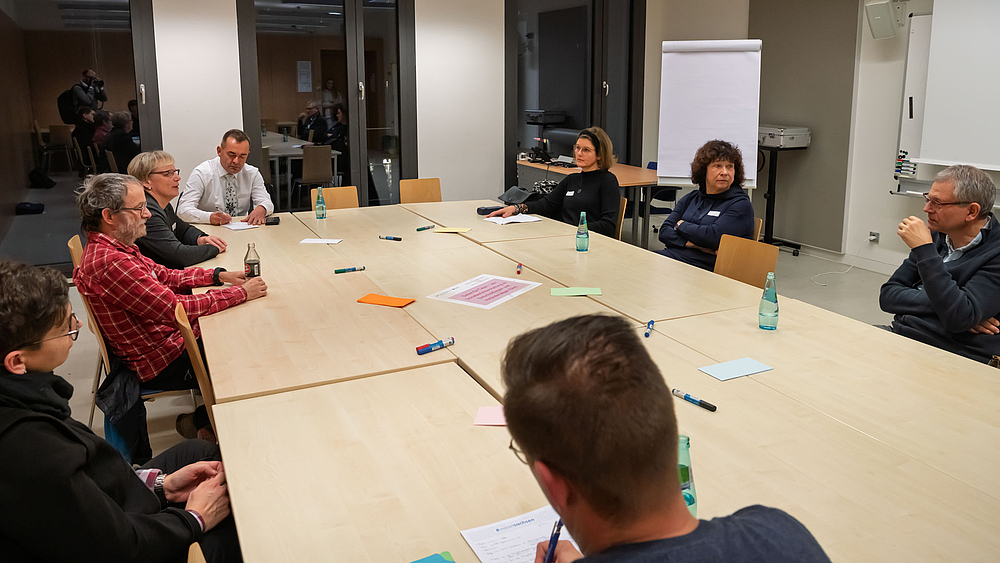 Acht Personen an einem großen Tisch im Gespräch