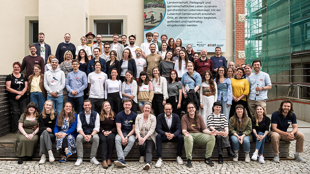 Auf den Stufen des Erfolgs: mehr als siebzig Menschen beim Gründungsforum in Mittweida. Gruppenfoto mit Personen die auf einem ansteigenden Podest vor einer Hauswand stehen.