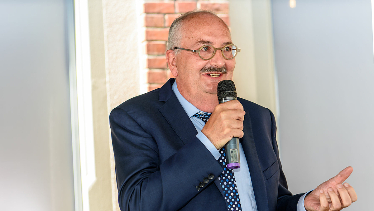 Das Foto zeigt den Rektor der Hochschule Mittweida, Prof. Ludwig Hilmer, bei seinem Grußwort. Er sagt: Ideen müssen geteilt werden. Dazu braucht der Ideen-Inkubator Glasscheiben, durch die man hinein- und hinausschauen kann.“