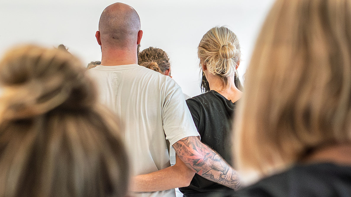 Blick von hinmtzen aif eine mänliche und eine weinhliche Peron, die sich an der Hüfte umarmen.