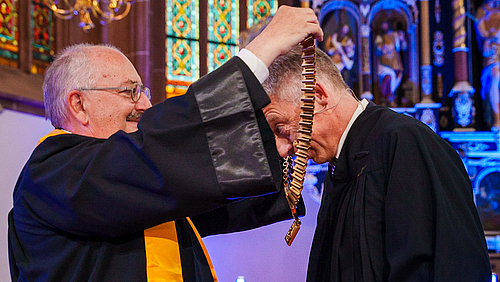 An die Kette gelegt: Professor Ludwig Hilmer legt seinem Nachfolger die Amtskette an: „Das ist jetzt Deine Hochschule.“ (Foto: André Wirsig)