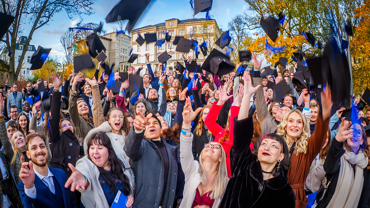 Das entstandene Foto mit jubelnden Absolvent:innen und fliegenden Hüten.