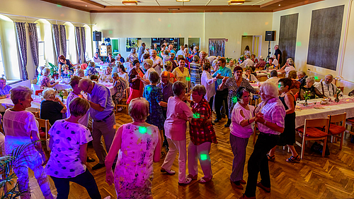 Volles Haus beim 2. Mittweidaer Seniorenball. Die Tanzfläche im Alten Schützenhaus Mittweida füllte sich schnell. Aus erhöhtem Standort zeigt das Foto einen Saal mit Parkettboden. Zwischen fast unbesetzten Tischen an der linken und rechten Seite des Saals ist die Tanzfläche gefüllt mit älteren tanzenden Paaren und im Vordergrund auch einzelnen Tänzerinnen.