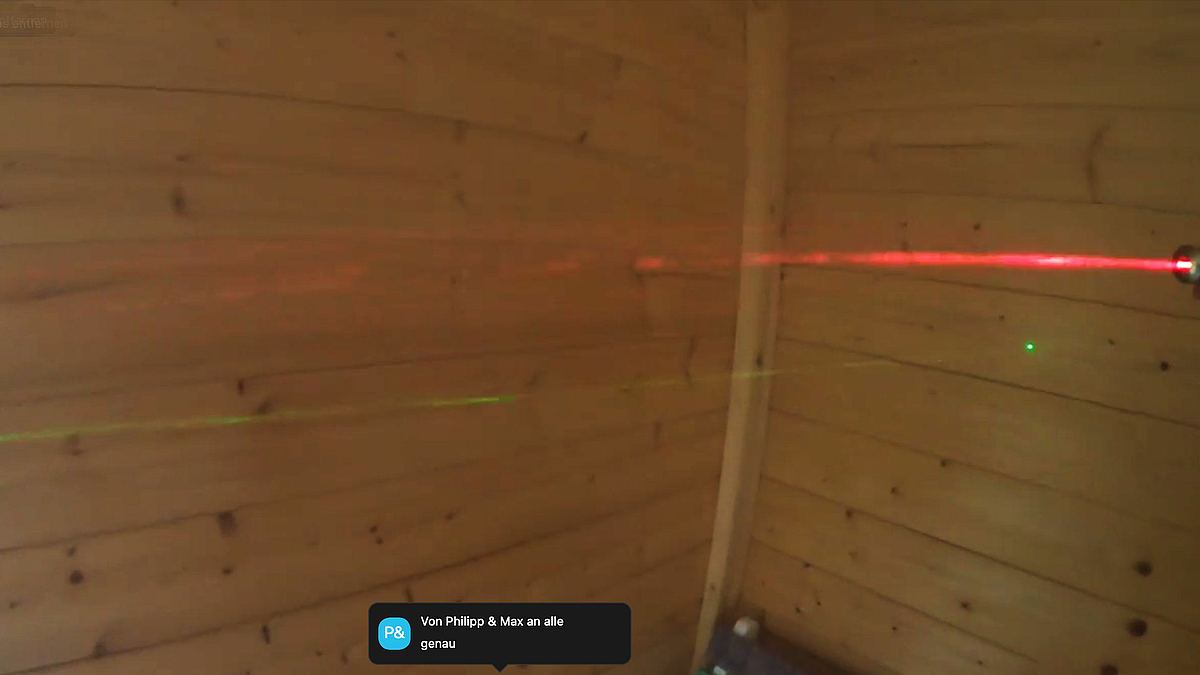 Der Screenshot zweigt zwei sich kreuzende Lichtstrahlen zweier Laserpointer, die mittels künstlich erzeugten Nebels sichtbar gemacht werden.