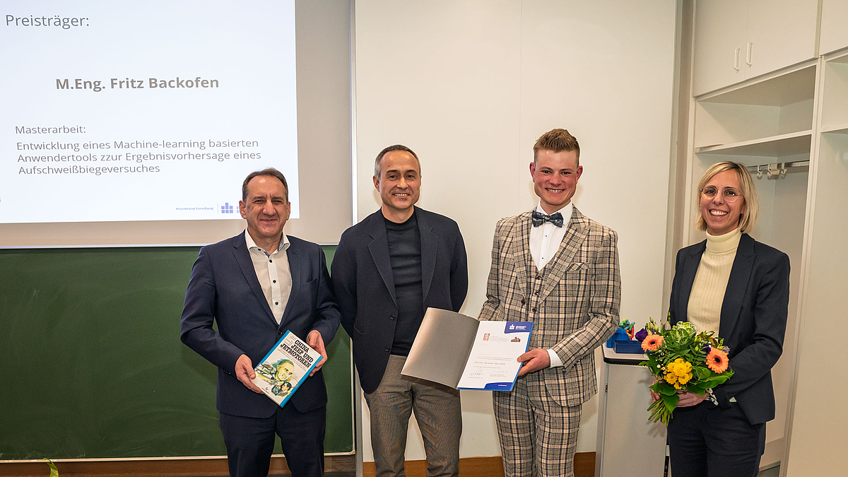 Preisträger Fritz Backofen zwischen Dekan Professor Michael Kuhl, dem Zweitprüfer seiner Masterarbeit Dr. Peter Kaiser, Geschäftsführer der CEWUS GmbH, und Erstprüferin Professorin Kristin Hockauf. Drei männliche und eine weibliche Person fröhlich