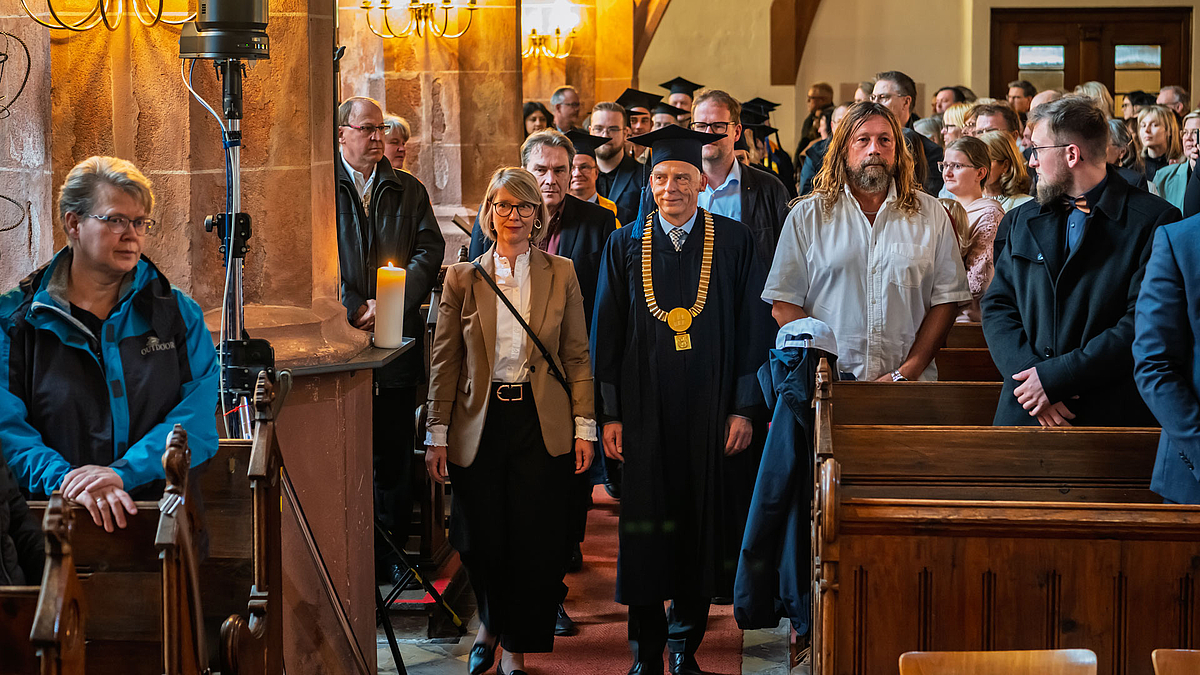 Einzug von Professor:innen in Talaren und Ehrengästen durch den Mittelgang des Kirchenschiffs.