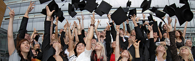 AbsolventInnen werfen ihre Hüte in die Luft