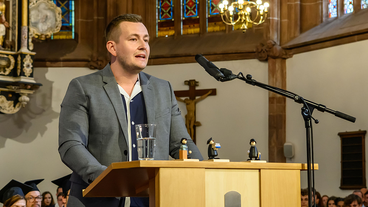 Gordon Guido Oswald, Geschäftsführer des Studierendenrats, lädt zur Mitarbeit in Projekten und Gremien ein. Er blickt auf die Resonanz für die Orientierungswoche zurück und ist „begeistert von euch Erstsemestern“.