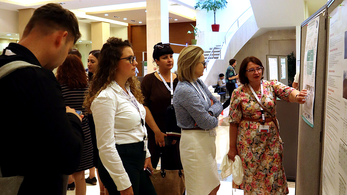 Neben den Vorträgen in mehreren Tracks bot die EURECA-PRO-Konferenz ebenfalls die Gelegenheit zur Poster-Präsentation. Vier Frauen stehen vor einem wissenschaftlichen Plakat an einer Poster-Tafel. Eine der Frauen erklärt den anderen den Inhalt ihrer Forschung.