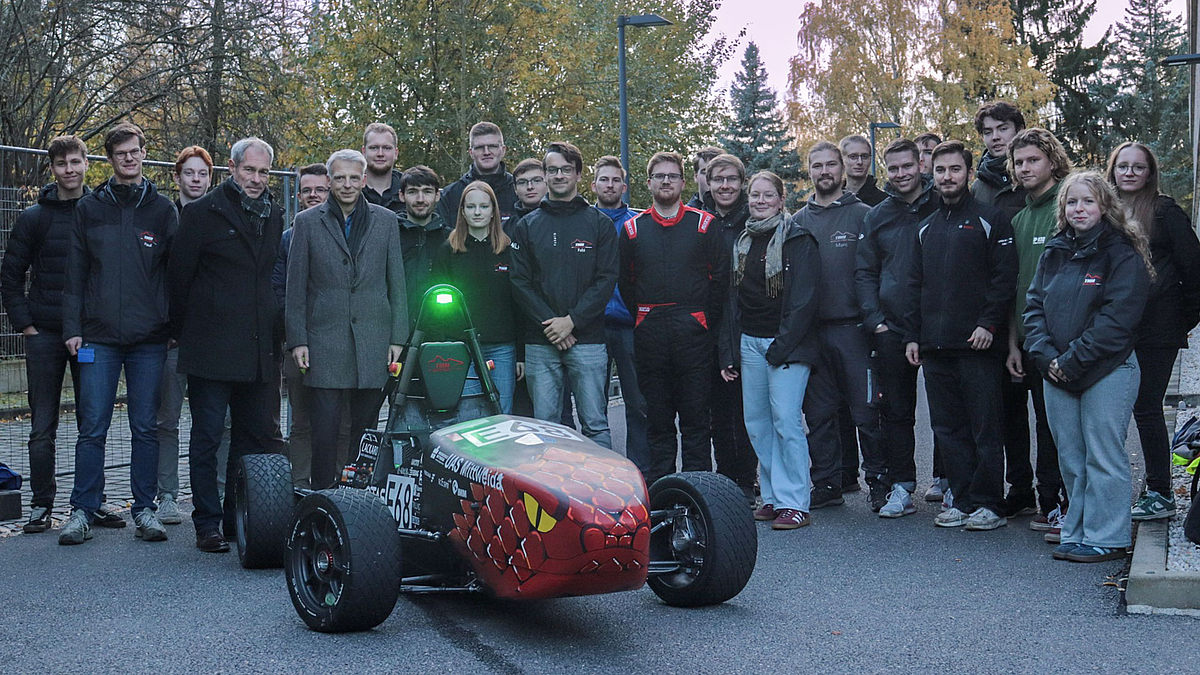 Gruppe aus 25 Personen hinter dem Rennauto