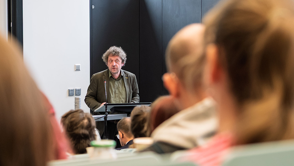 Blick zwischen den Köpfen der Zuhörenden auf den denselben Redner .