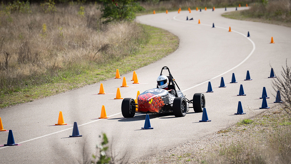 Rennauto durchfährt eine mit Polynen markierte Kurvenstrecke.