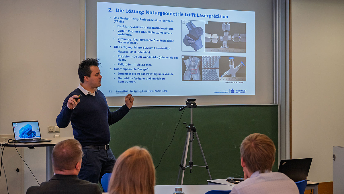 Platz zwei: Justus Reuter Männliche Person vor projizierter Powerpointpräsentation. Im Vordergrund Köpfe des Publikums von hinten.