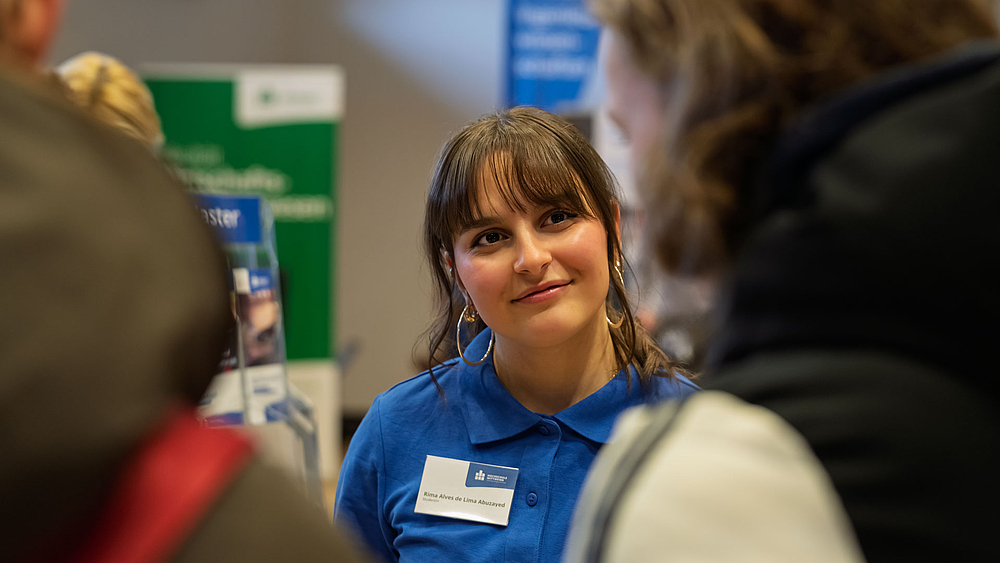 Junge Frau mit baluen HSMW-Poloshirt im Gespräch.