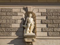 Eine von zwei Figuren an der Fassade zeigt Hephaistos, den griechischen Gott des Feuers und der Metallkünste; die andere ist Elektra.