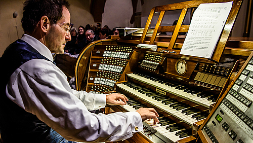 Foto aus der Adventszeit 2018 mit Gästen auf der Orgelempore: Prof. Frank Czerner an der Ladegast-Jehmlich-Orgel der Stadtkirche. Das Foto zeigt einen Organisten an einem dreimanulaligen Spieltisch.