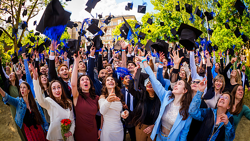 Immer wieder gern gemacht, immer wieder gern gesehen: „Geschafft!“ heißt es, wenn die Hüte vor der Hochschule fliegen. (Foto: André Wirsig) Viele fröhliche junge Menschen werfen ihre Abschlusshüte in die Luft.