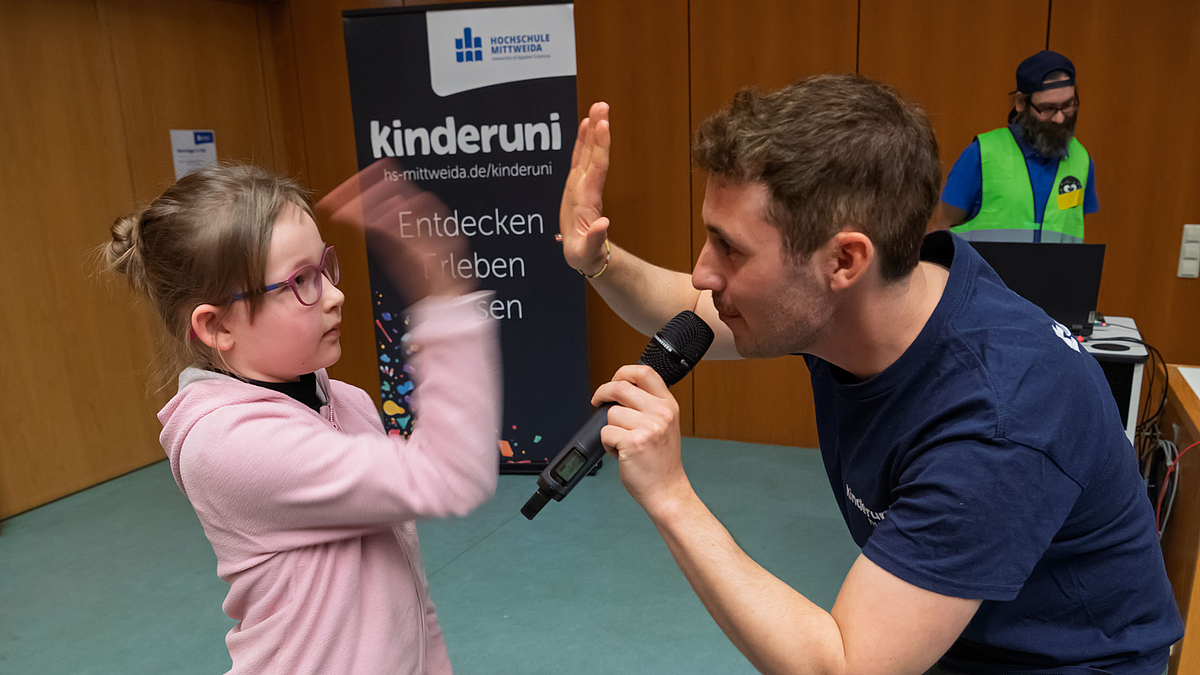 Ein Mädchen und der Moderator mit Mikrofon und klatschen sich ab.