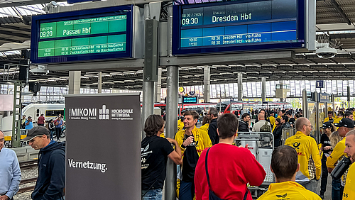 Abfahrt in der Kulturhauptstadt. Das Ziel der gemeinsamen Vernetzungs-Tour von Engagierten aus Sport, Wirtschaft und Wissenschaft ist Passau: Start des European Peace Ride 2025. Menschen, darunter viele Sportler im gelben DHL-Trikot an einem Bahnsteig.