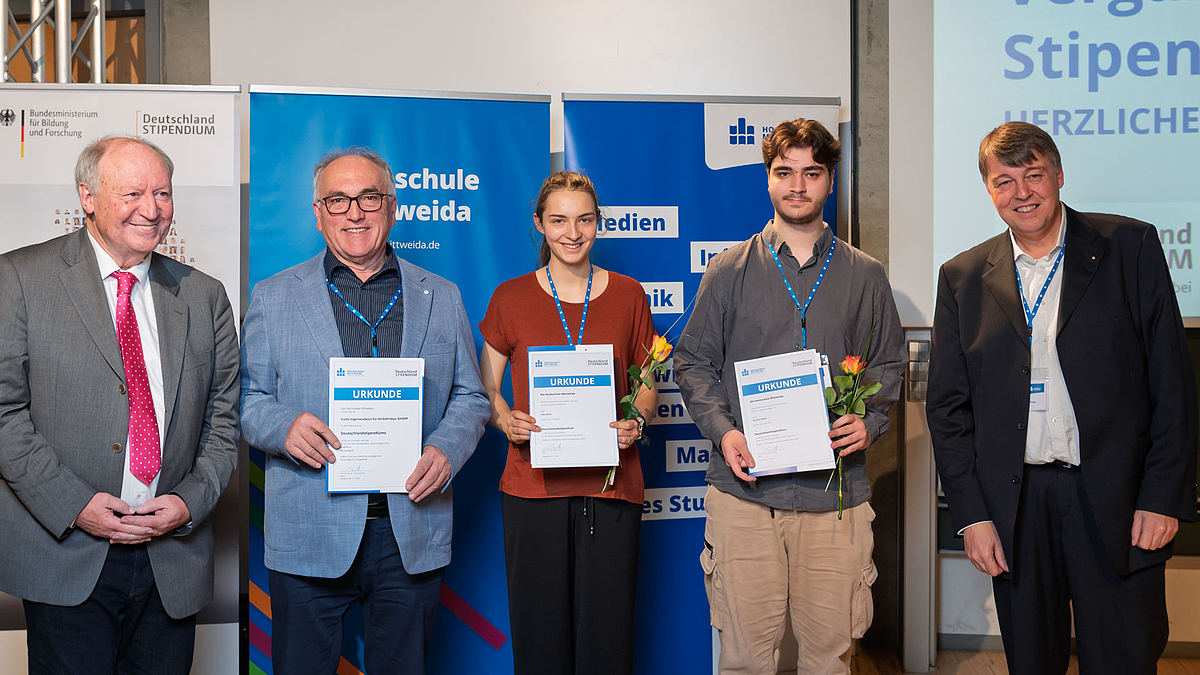 Eine Stipendiatin und ein Stipendiat jeweils mit Urkunde zwischen drei männlichen Personen.